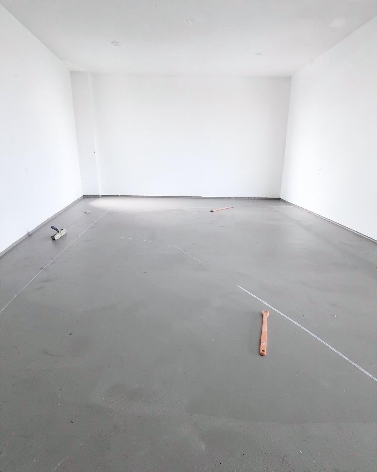 Bare concrete subfloor in an empty room marked with layout lines, ready for flooring installation