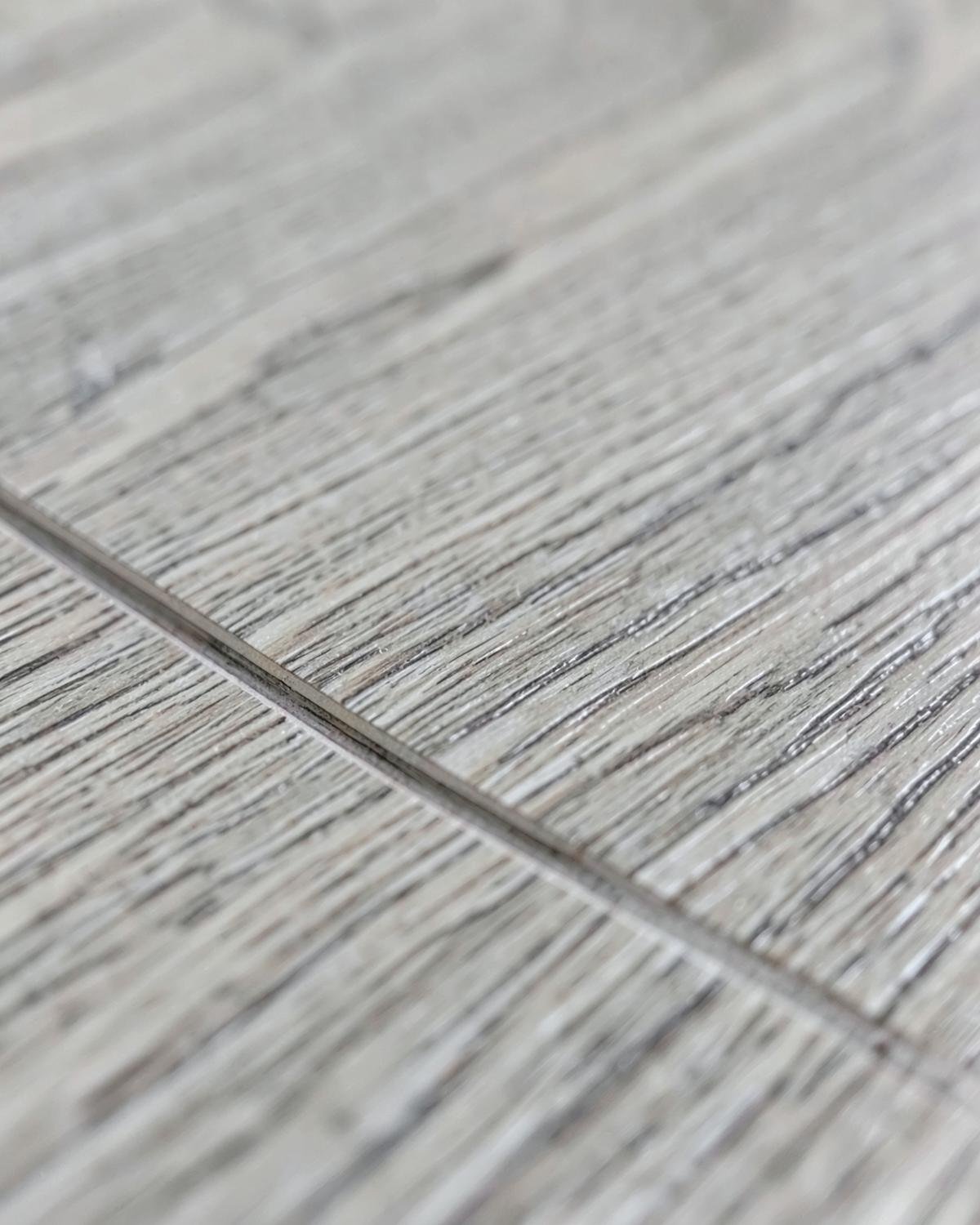 Close-up of light gray wood-look plank flooring showing the seam between two boards